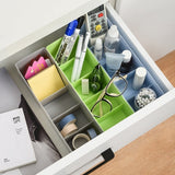 Clear plastic storage tray with dividers, used for organizing various small craft items.